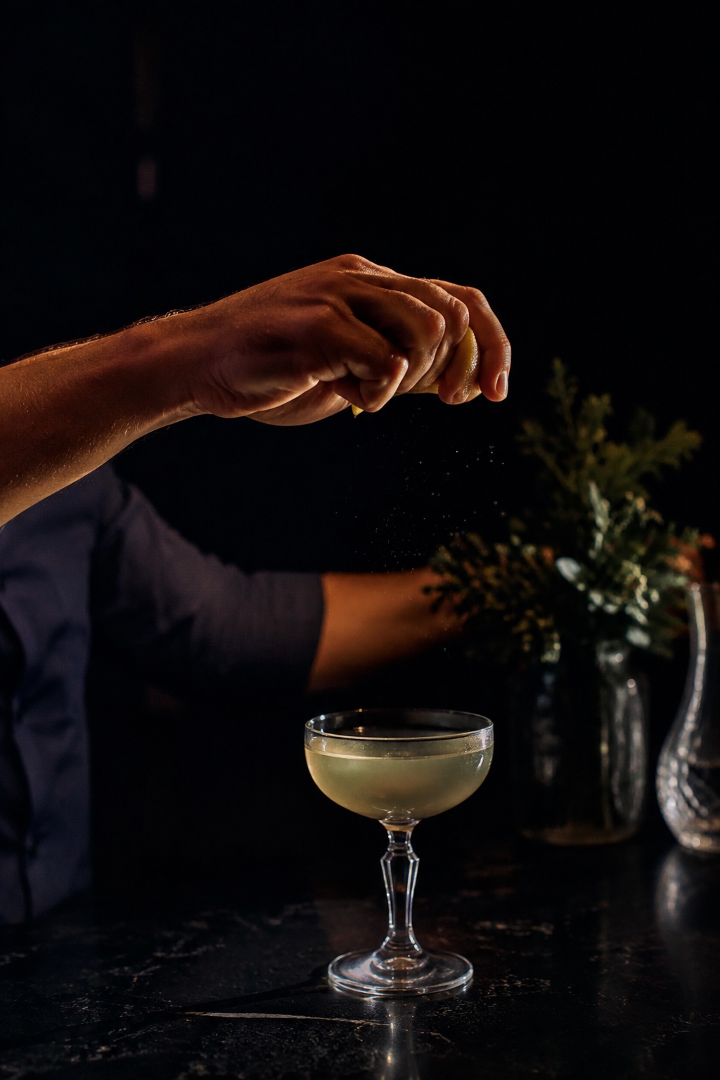 Main d’un barman zestant un agrume au-dessus d’une coupe